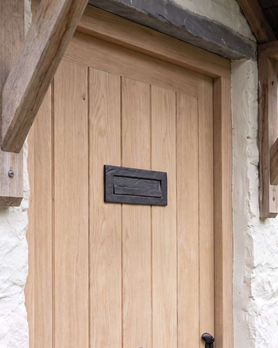 Smooth black iron letter plate on a pale oak ledged cottage front door
