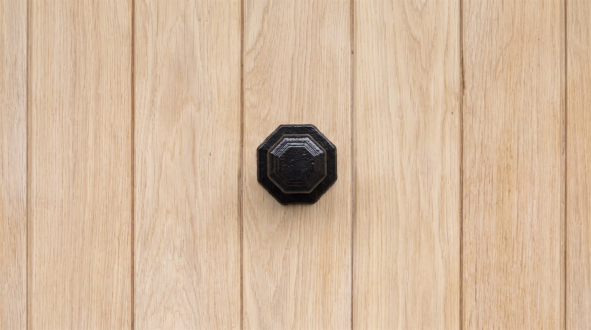 Smooth black iron octagonal centre knob on a pale oak ledged cottage front door