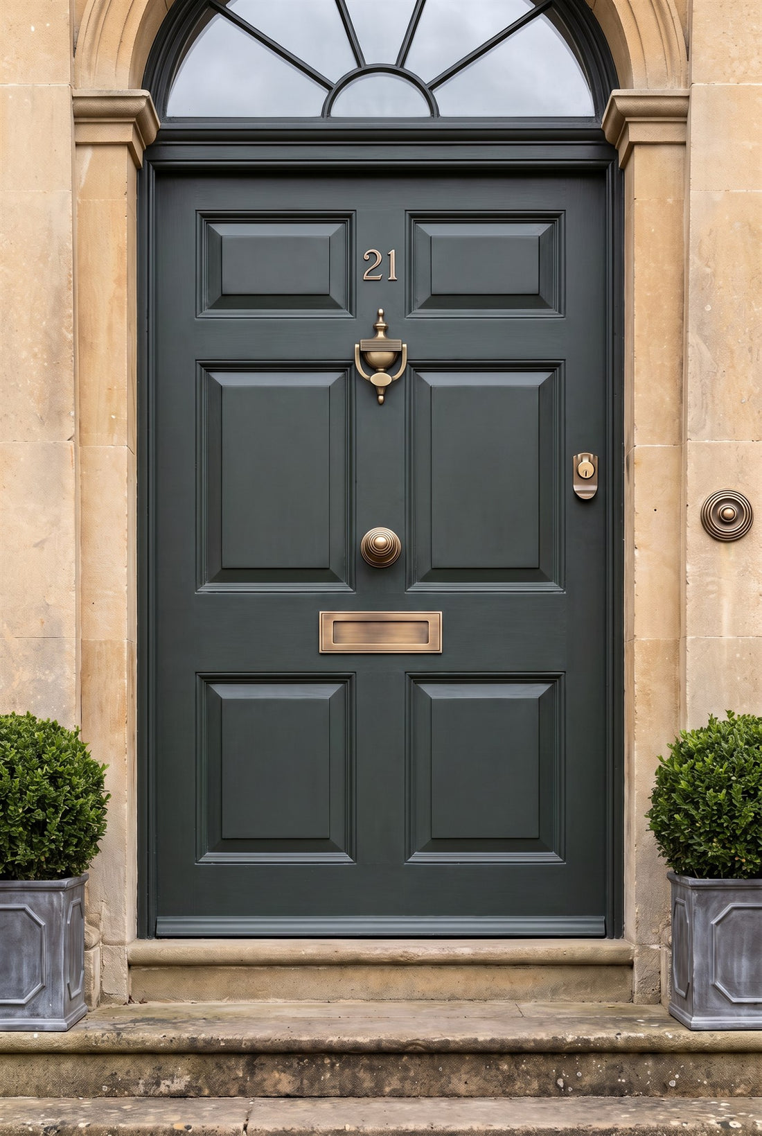 Deep smoky green six-panel front door in a Bath stone doorcase with a semicircular fanlight, fitted with antique brass number 21, reeded urn knocker, reeded centre knob, letter plate, cylinder pull and reeded bell push
