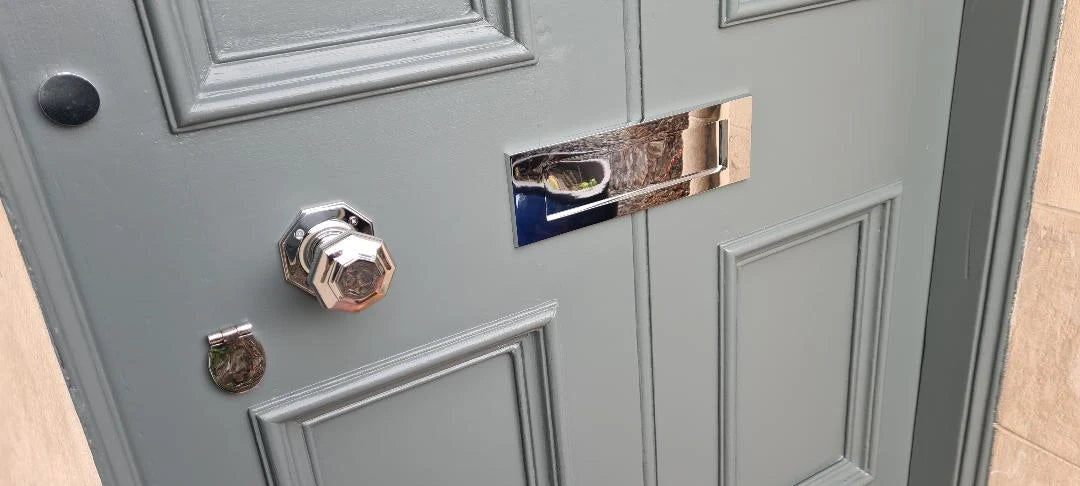 Decorative front door ironmongery including a polished door knob and letter plate