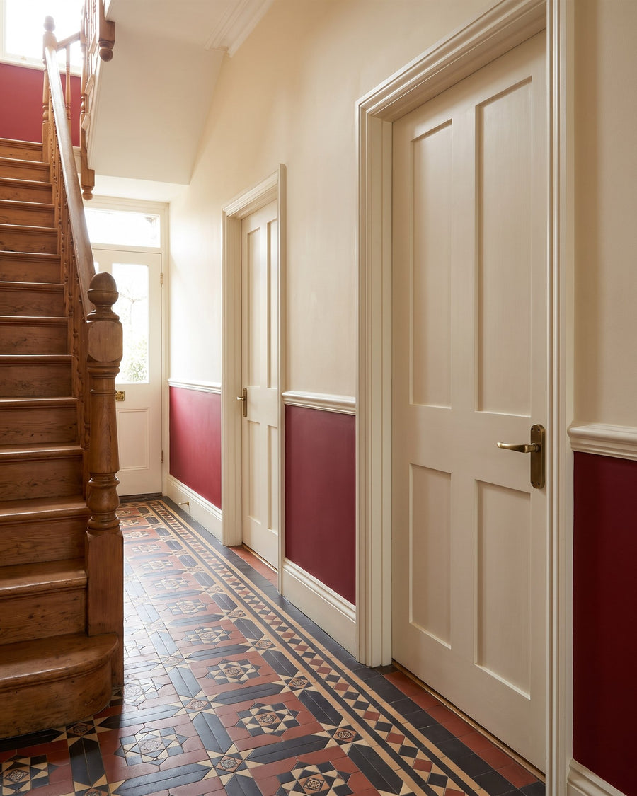 Victorian hallway with encaustic tiles, a red dado and cream four-panel doors with antique brass Gloucester lever handles